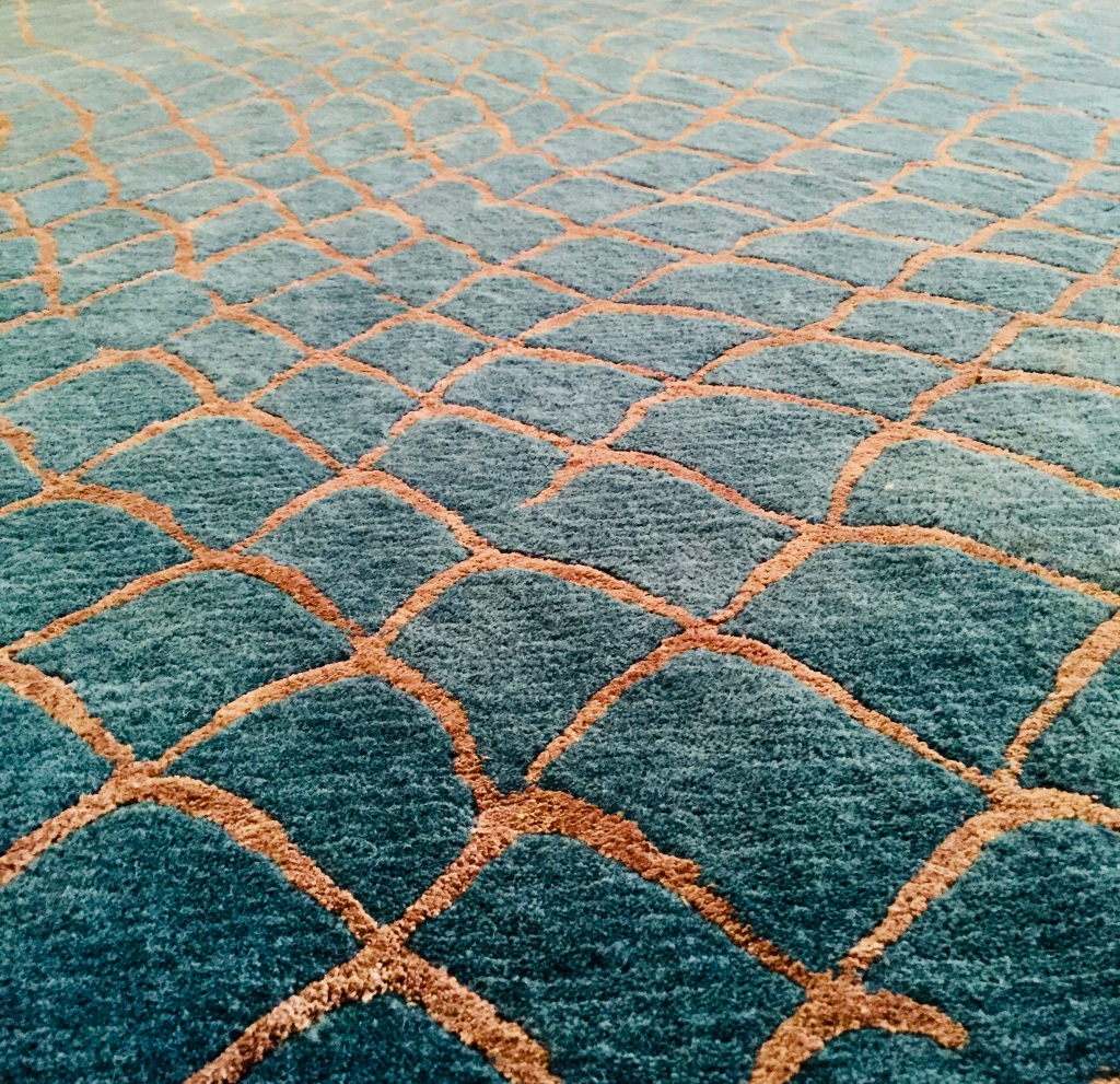Tapis sur mesures, avec un motif qui rappelle les vagues et les couleurs choisies pour représenter l'eau et le reflet doré du soleil.